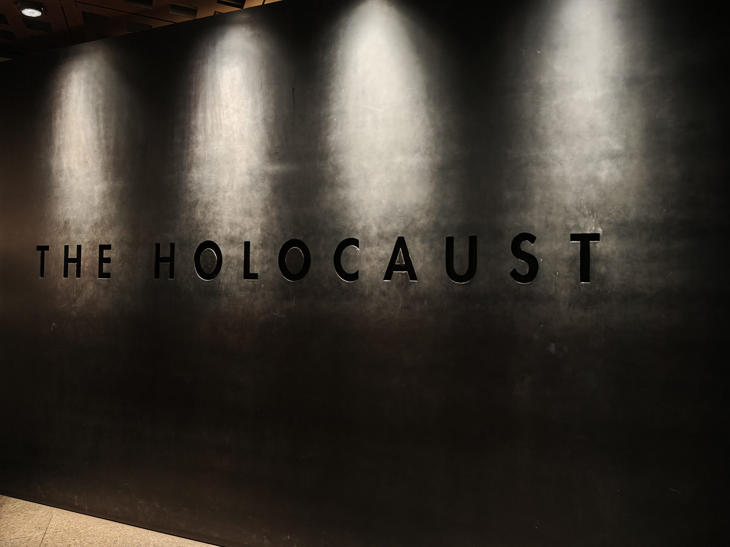 Schriftzug HOLOCAUST an einer dunklen Wand im Museum